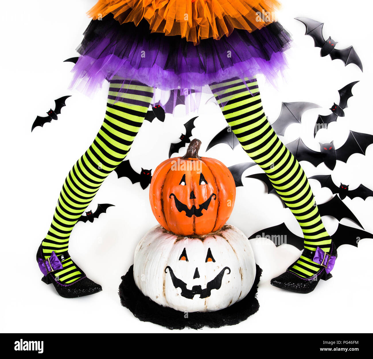 Funny verde rigato nero gambe di una bambina con il costume di halloween di una strega con scarpe strega e smiley zucca di halloween jack o lantern Foto Stock