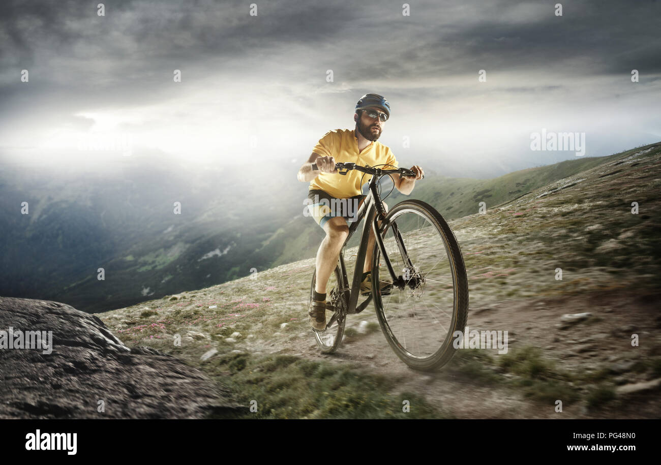 Il giovane montare gli uomini nel casco di conquistare le montagne su una bicicletta. La moto, natura, bicicletta, sport, ciclo, extreme, lifestyle, avventura e sport concept Foto Stock