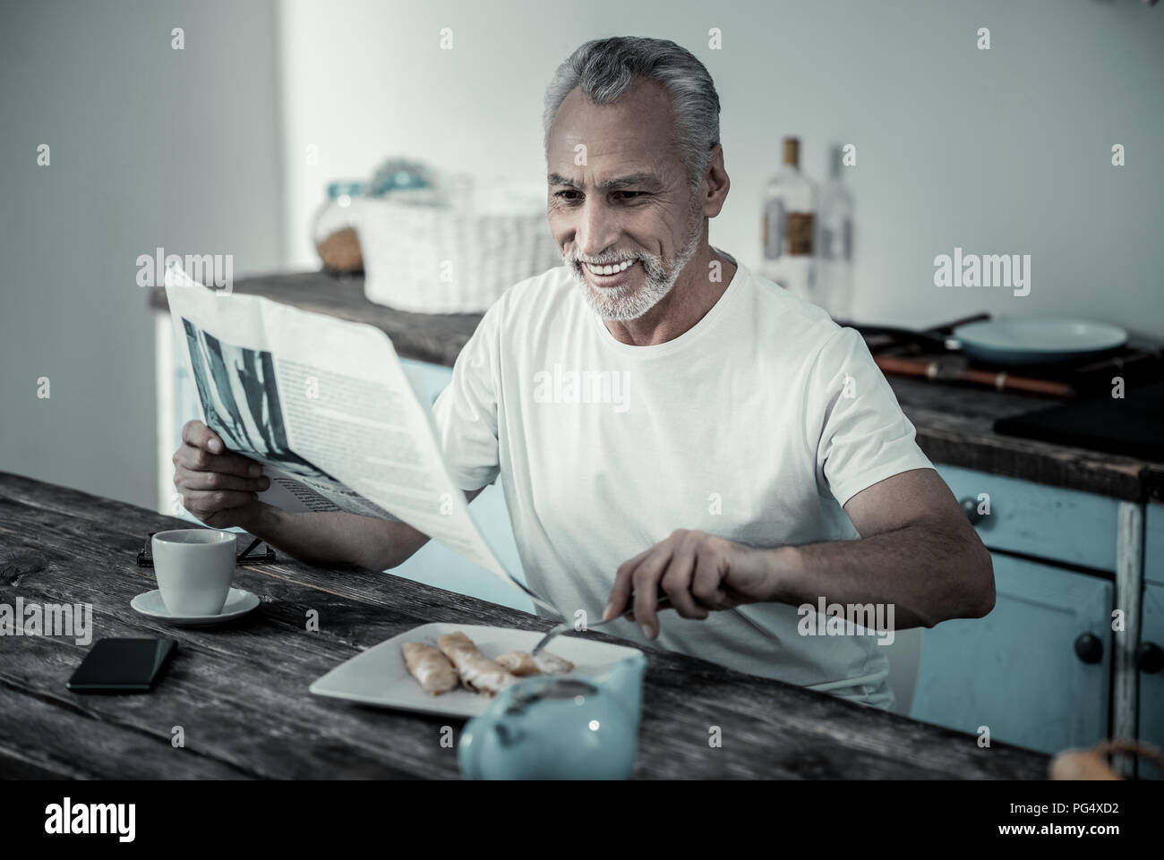 Gioioso maschio in pensione per leggere le notizie Foto Stock Gioioso maschio in pensione per leggere le notizie Foto Stock