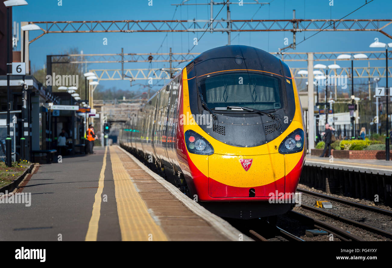 Treni del Virgin pendolino classe 390 electric treno ad alta velocità che arrivano in corrispondenza di una stazione ferroviaria sulla linea di Abbazia, Hertfordshire, Regno Unito. Foto Stock