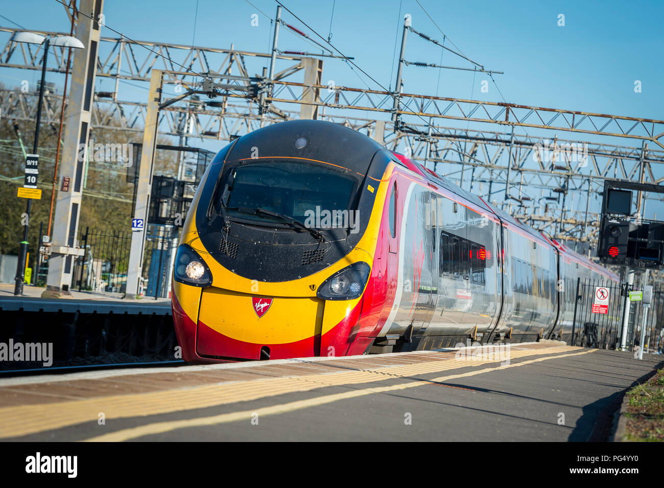 Treni del Virgin pendolino classe 390 electric treno ad alta velocità che arrivano in corrispondenza di una stazione ferroviaria sulla linea di Abbazia, Hertfordshire, Regno Unito. Foto Stock