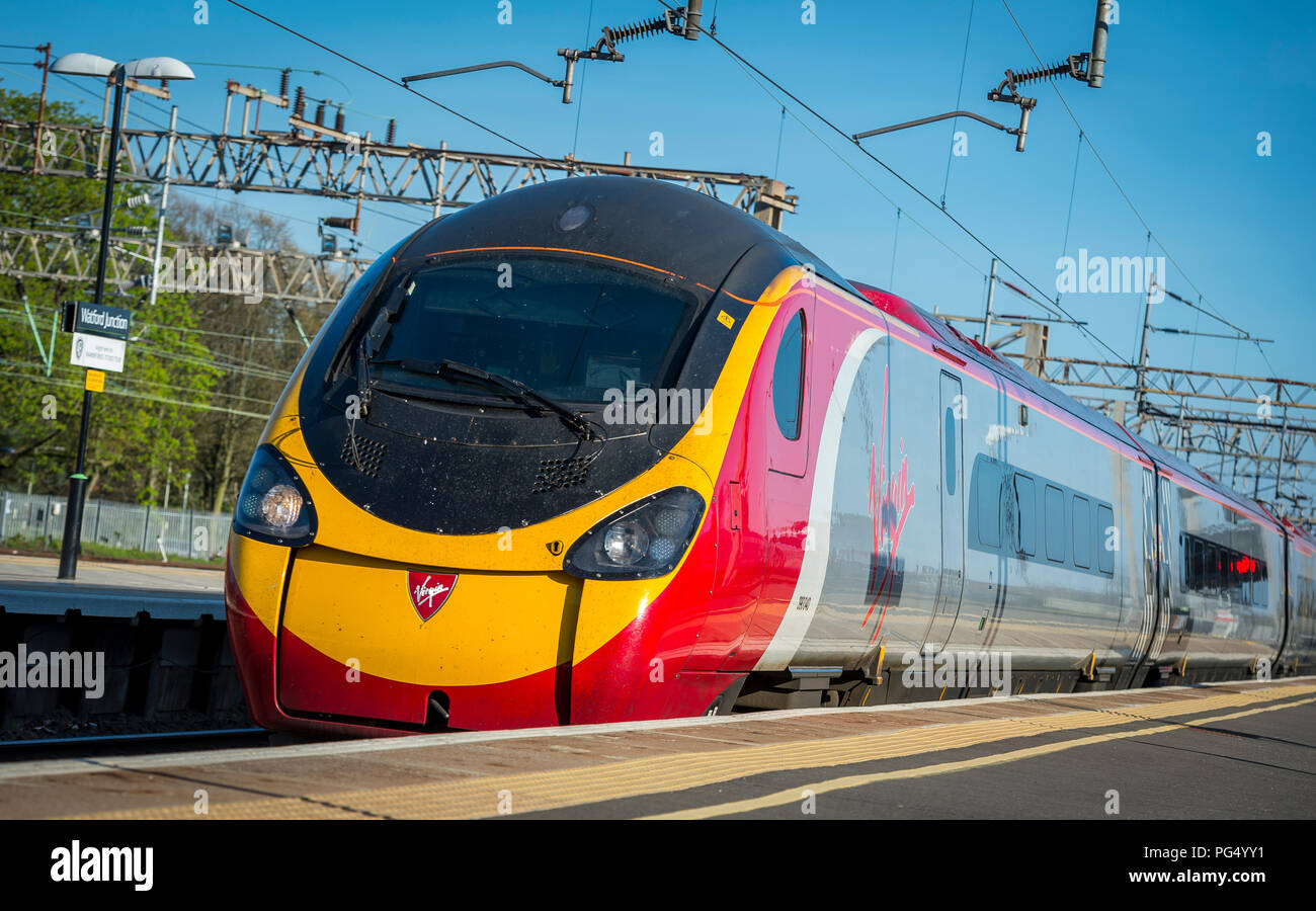 Treni del Virgin pendolino classe 390 electric treno ad alta velocità che arrivano in corrispondenza di una stazione ferroviaria sulla linea di Abbazia, Hertfordshire, Regno Unito. Foto Stock