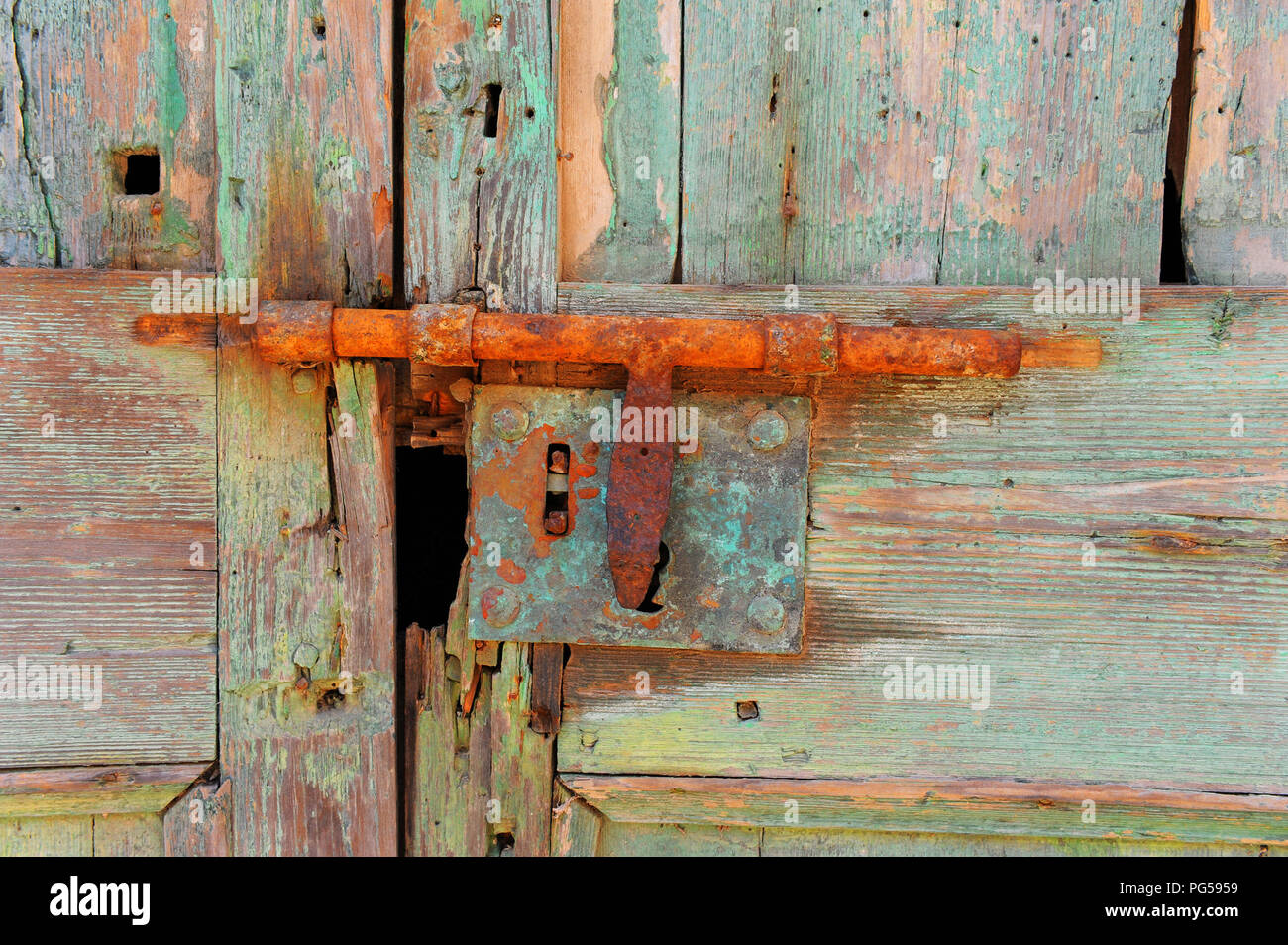 Colori vivaci di bulloni arrugginiti su una vecchia porta di legno rotta e maltempo. Minorca, Spagna. Foto Stock