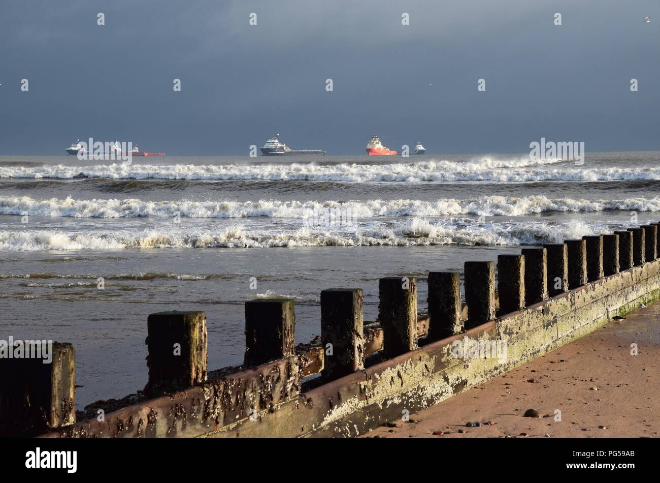 Alimentazione olio di navi a Aberdeen spiaggia con pennelli in primo piano. Foto Stock