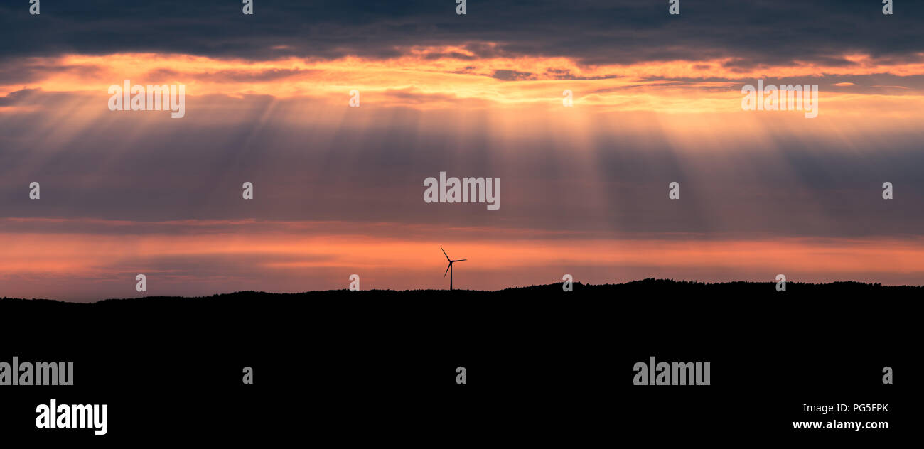 Un solitario windturbine su una collina al tramonto vicino Uddevalla, presso la westcoast della Svezia. Raggi crepuscolari (più comunemente noto come raggi solari) Foto Stock