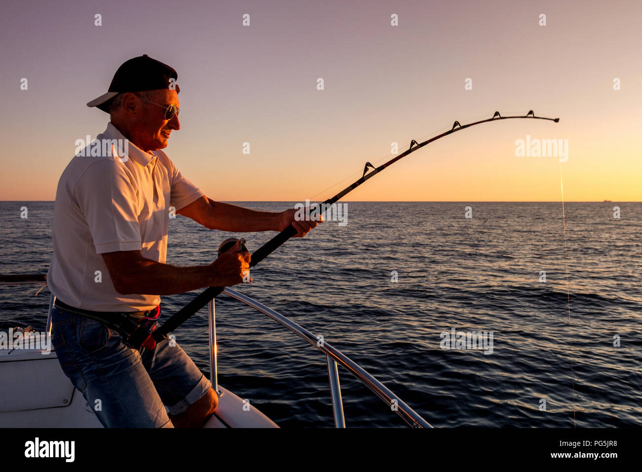 Il pescatore pesca in mare dalla barca al tramonto Foto stock - Alamy