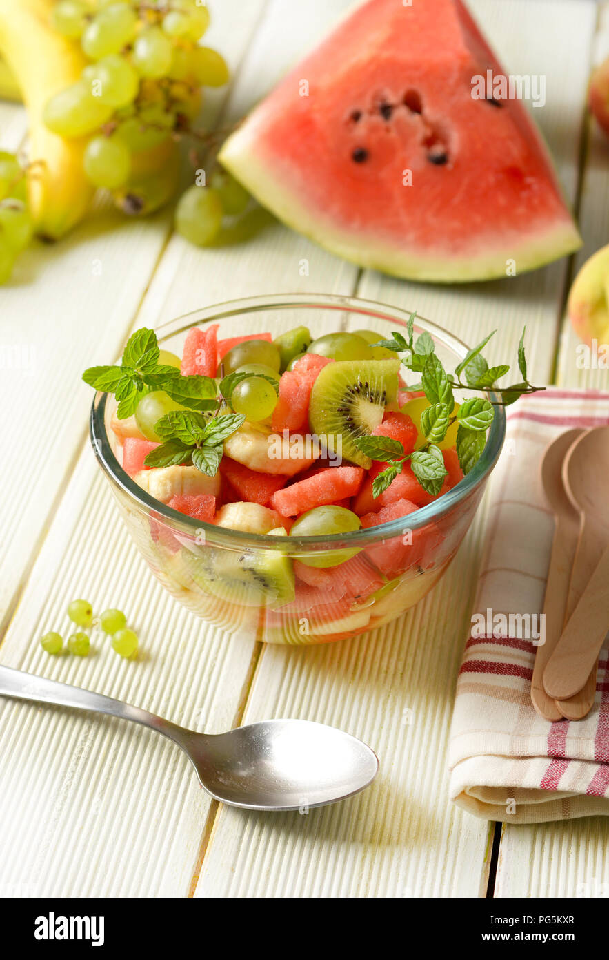 Estate insalata di frutta nel recipiente di vetro - cocomero, pesche, uva, banana e kiwi - primo piano Foto Stock