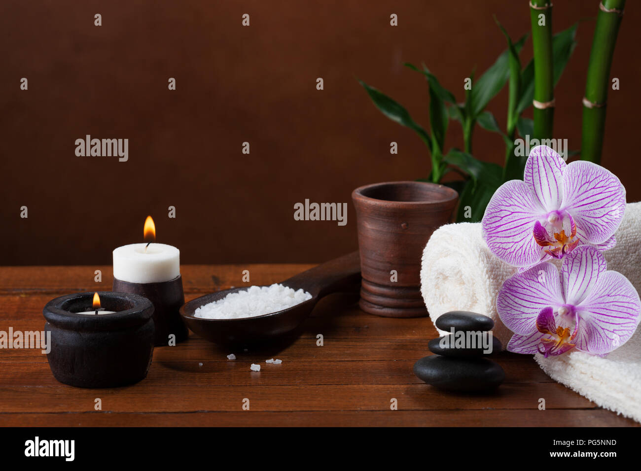 Impostazione di Spa con sale marino, candele, asciugamani, pietre e orchidee. Foto Stock