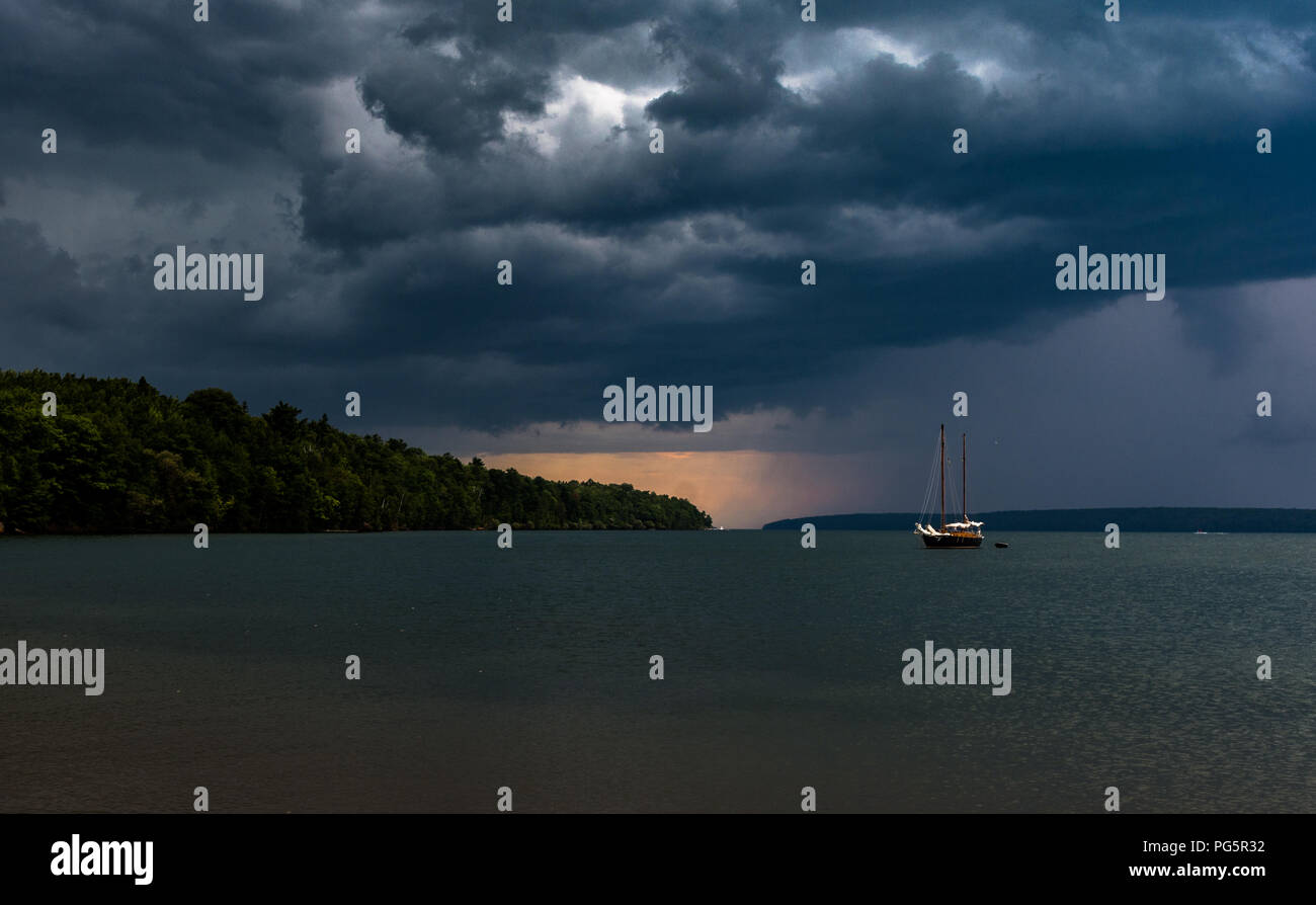 Barche a vela ComingSail Storm barca su acqua grigia nubi e pioggia in horizen Foto Stock