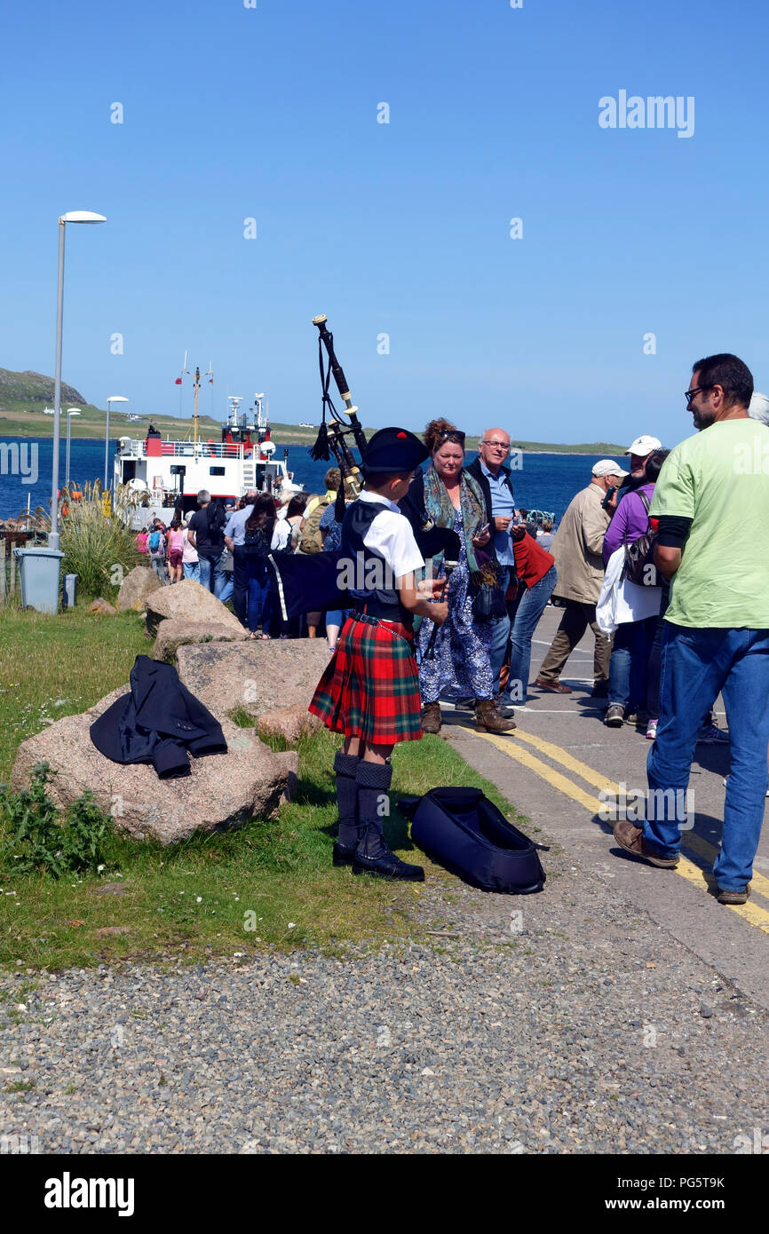 Giovani piper intrattenere il Calmac traghetto passeggeri di accodamento per Iona a Fionnphort sull'Isle of Mull Foto Stock