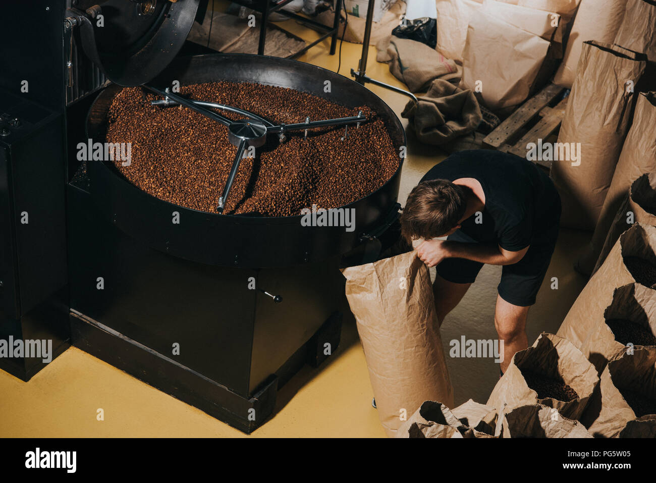 Uomo di riempimento sacchetto di carta di fresco con chicchi di caffè tostati Foto Stock