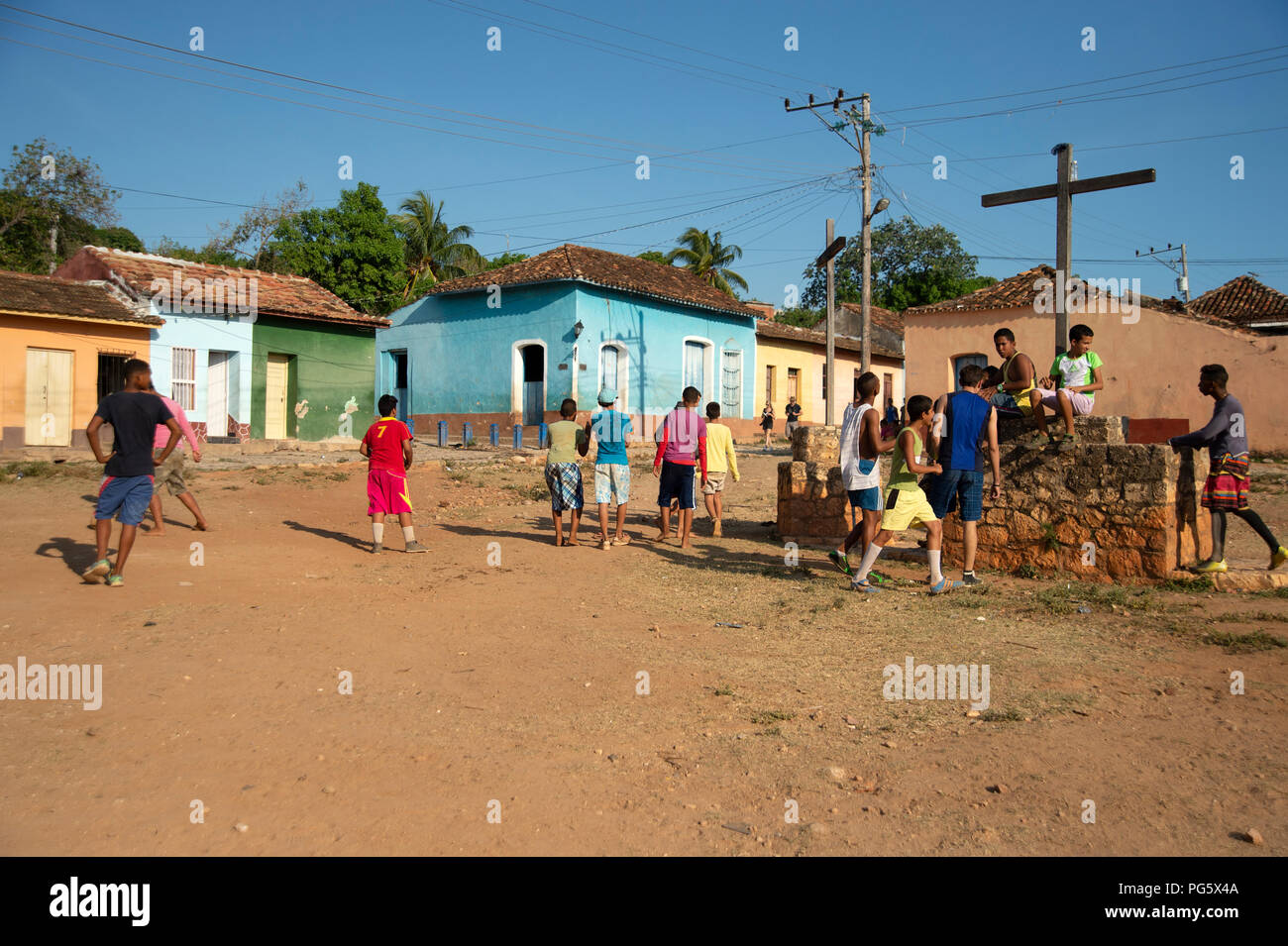 Gli adolescenti cubani a giocare il gioco del calcio sulla massa di rifiuti in Trinidad con casa tradizionale in background Foto Stock