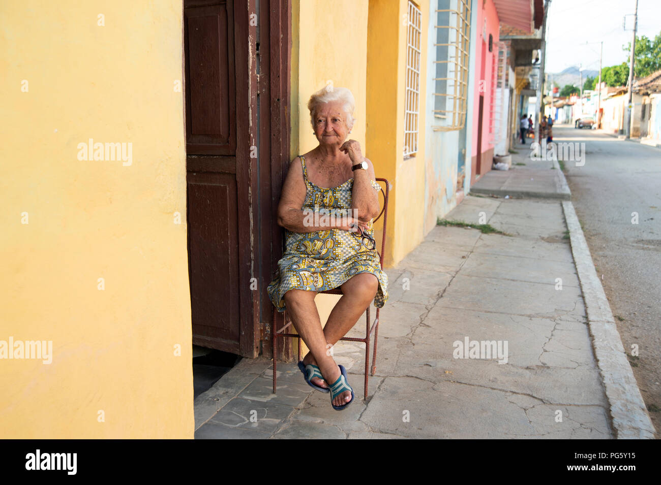 Anziani spagnolo/donna cubana seduto su una sedia al di fuori di casa sua in serata in Trinidad, Cuba Foto Stock