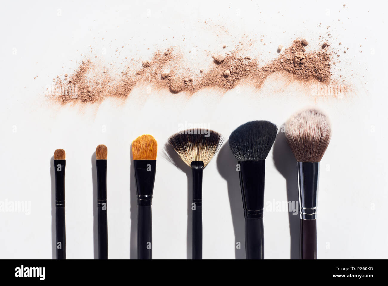 Linea di sparse in polvere per il viso e make up pennelli su sfondo bianco Foto Stock