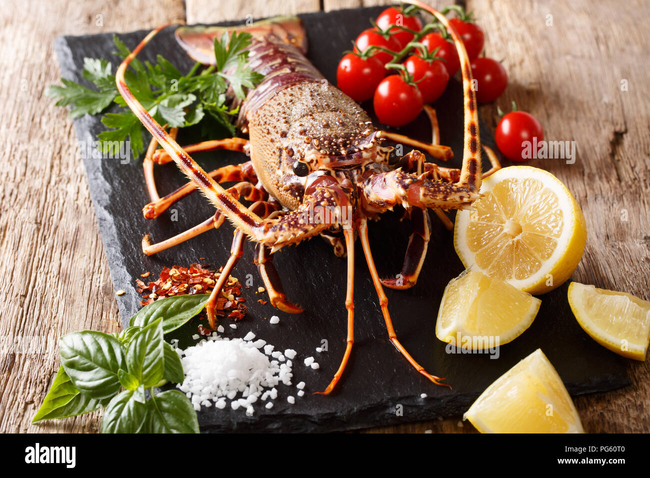 Delizioso cibo crudo: Aragosta con pomodoro, limone e le erbe, sale close-up su una scheda di colore nero. Posizione orizzontale Foto Stock