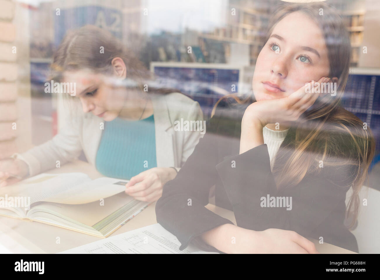 Ritratto di daydreaming ragazza adolescente in una biblioteca pubblica guardando fuori della finestra Foto Stock