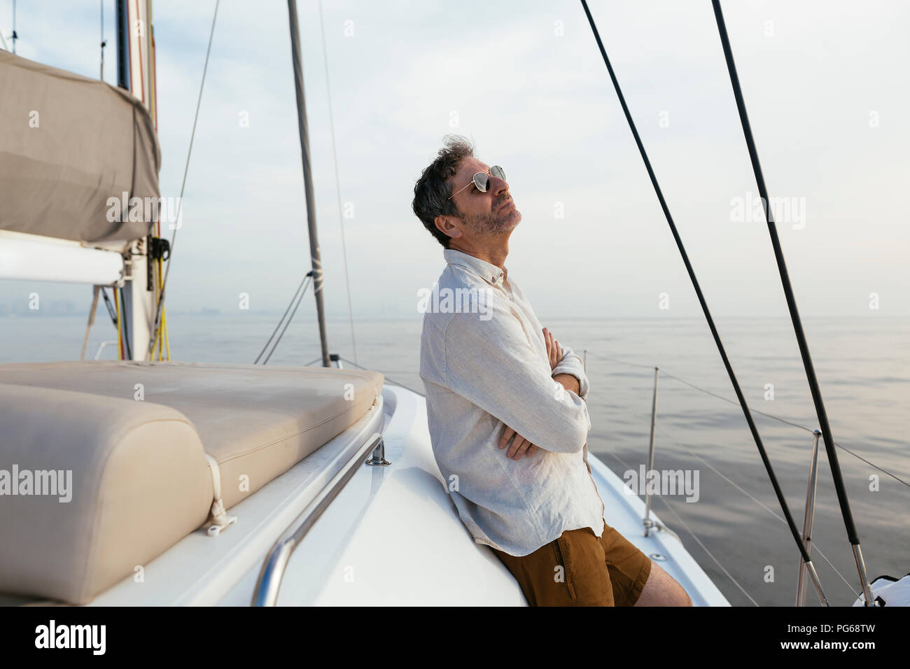 Uomo Marure sul catamarano con le braccia incrociate, godendo della brezza Foto Stock