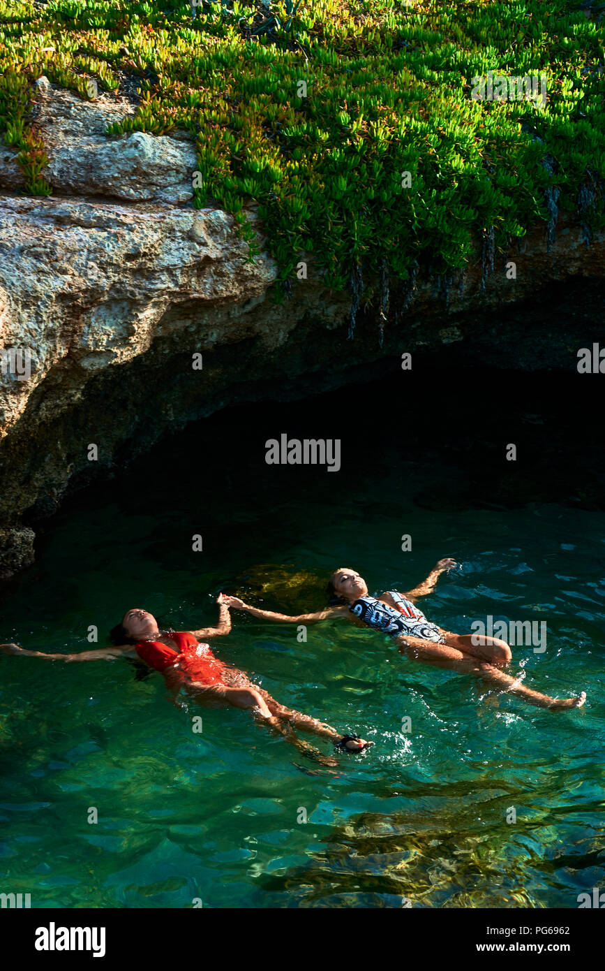 Giovani donne galleggiante sull'acqua in laguna Foto Stock