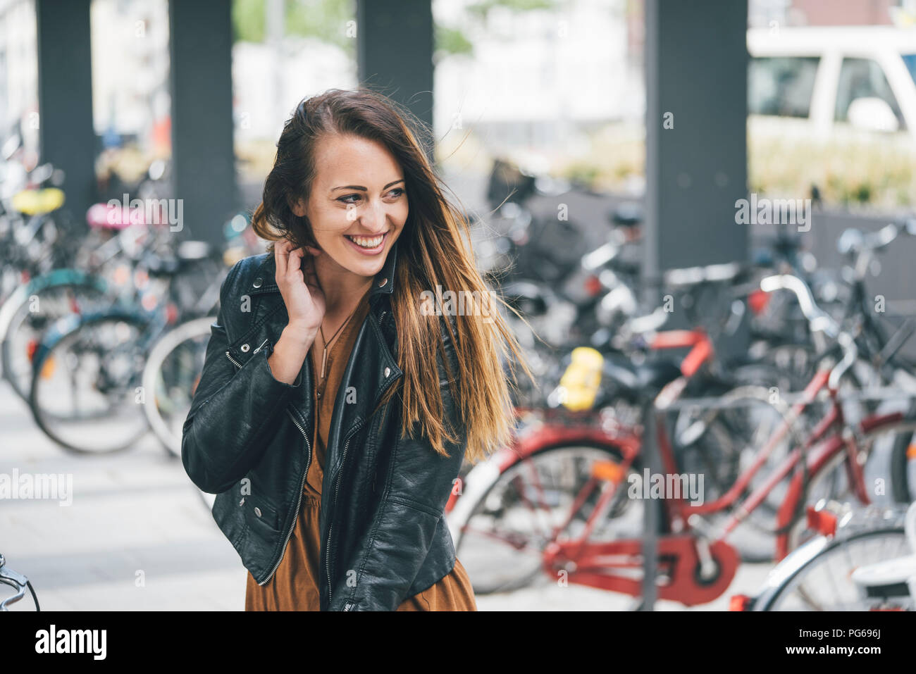 Ritratto di felice giovane donna presso il parcheggio per le bici in stazione in città Foto Stock