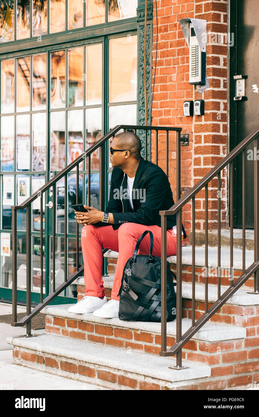 Stati Uniti d'America, New York, Brooklyn, uomo in attesa su scale, utilizza lo smartphone Foto Stock