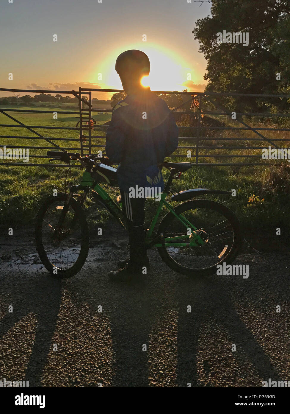 Tramonto dietro la gioventù in bicicletta, in campagna, al crepuscolo Foto Stock