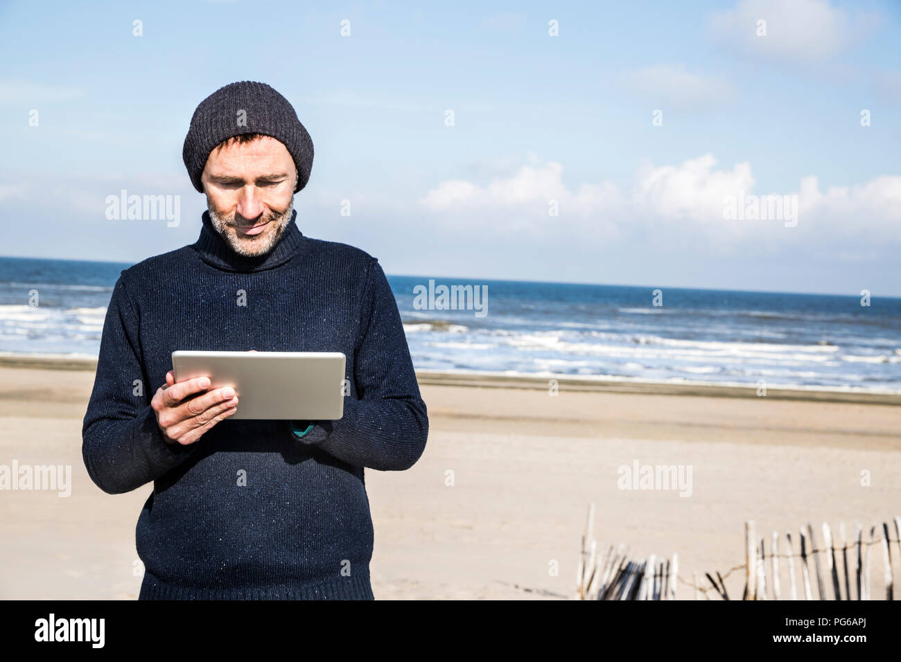 Uomo che utilizza tablet sulla spiaggia Foto Stock