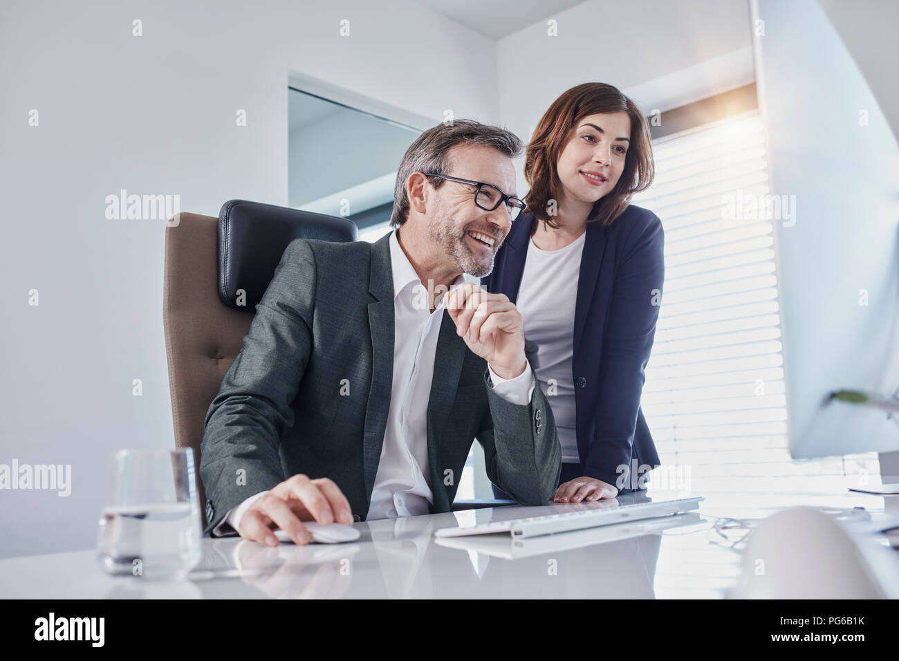 Imprenditore sorridente e imprenditrice guardare il computer alla scrivania in ufficio Foto Stock