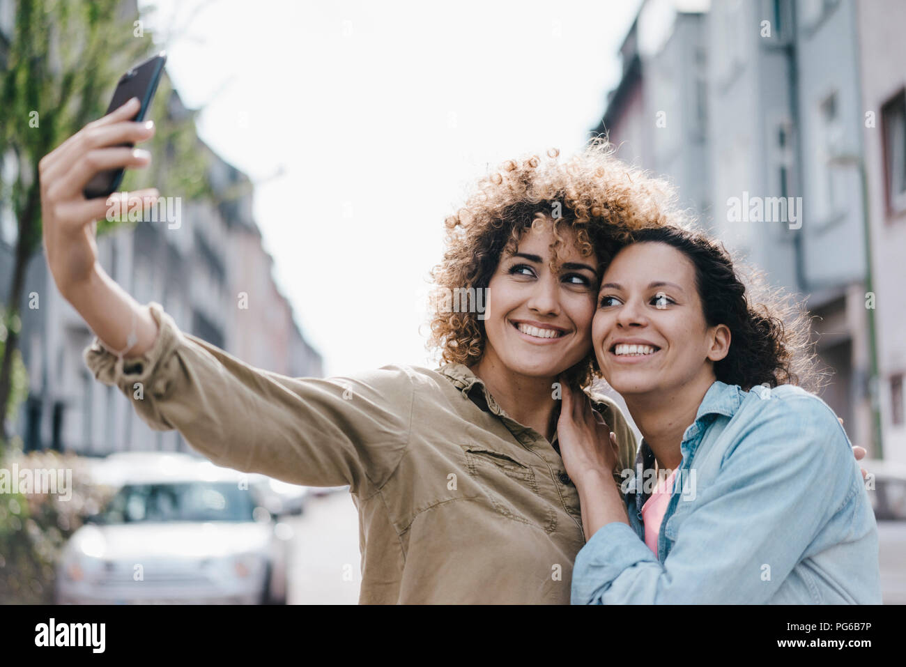 Migliori amici prendendo selfies con uno smartphone in città Foto Stock