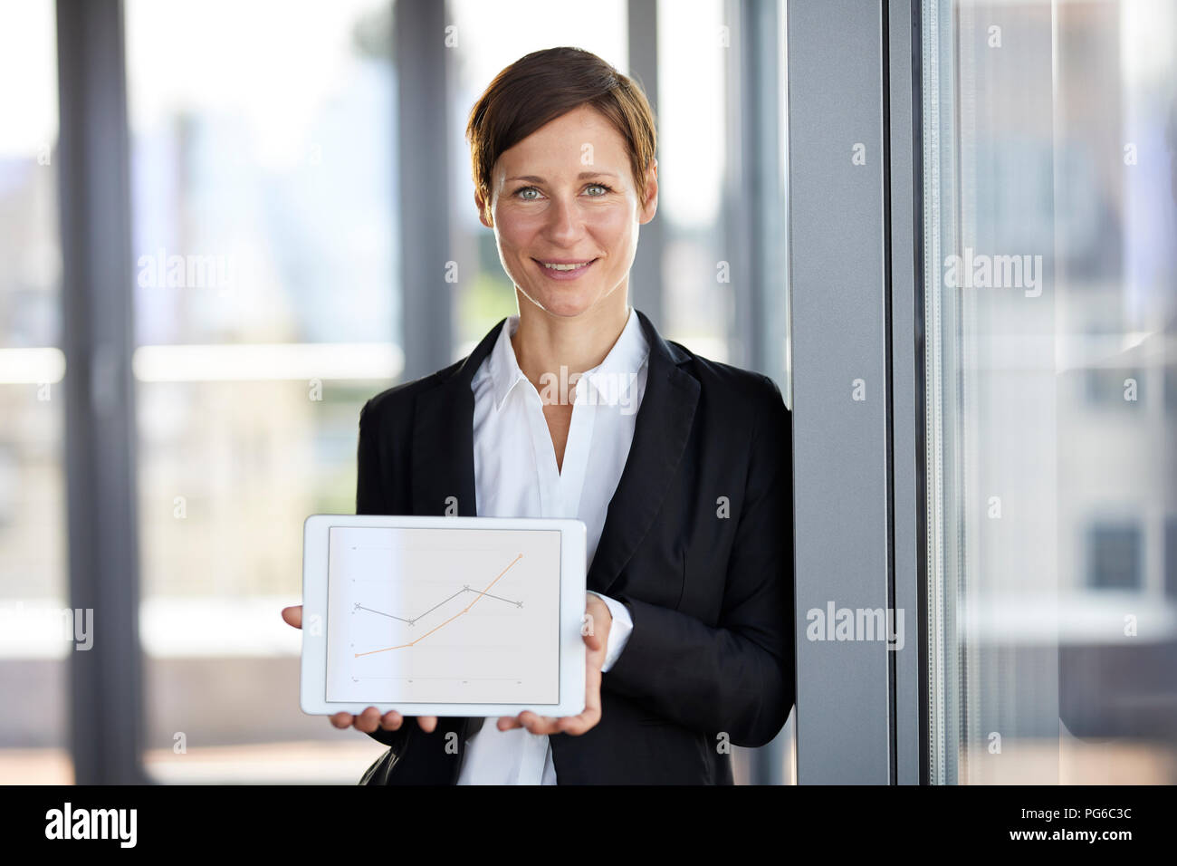 Ritratto di imprenditrice sorridente in ufficio azienda tablet mostra linea ascendente grafico Foto Stock