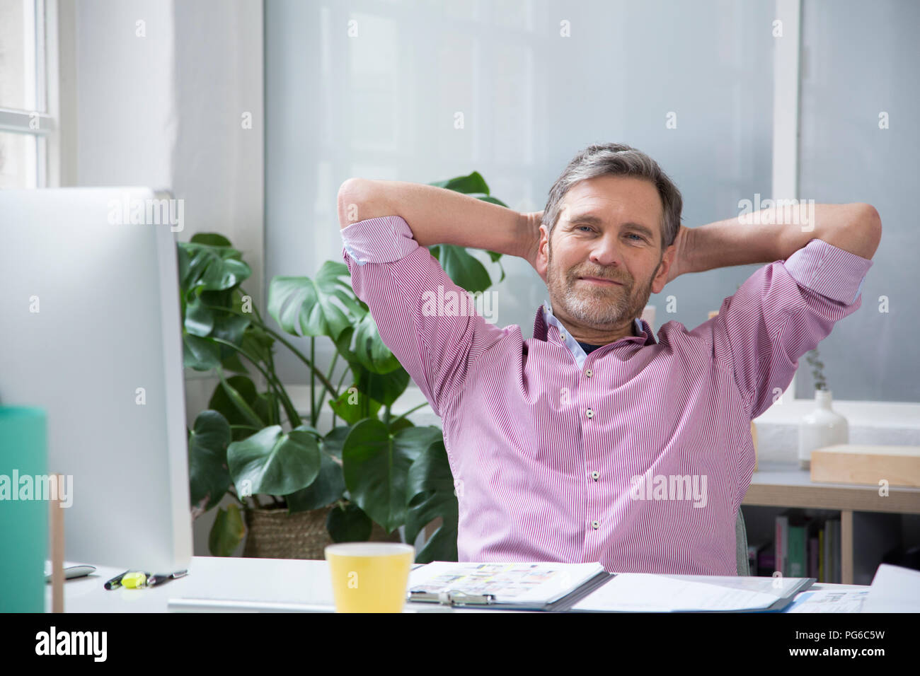 Ritratto di un fiducioso Uomo alla scrivania in ufficio Foto Stock
