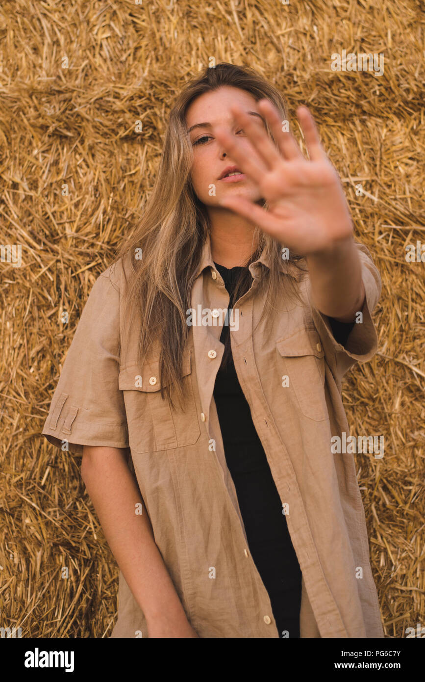 Giovane donna in piedi di fronte a balle di fieno facendo respingendo la mano gesto, ritratto Foto Stock