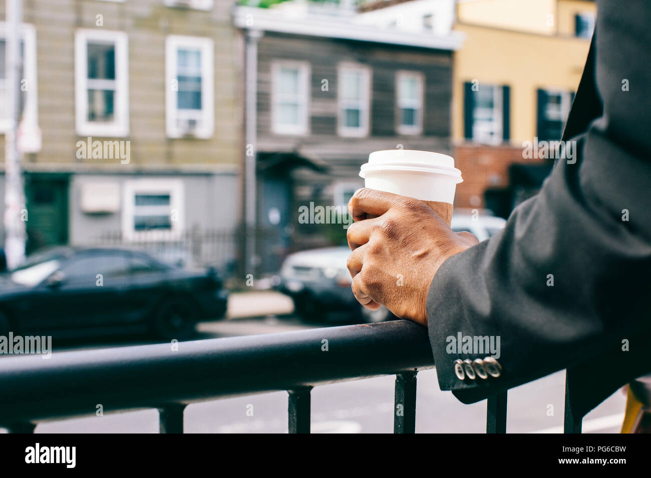 Le mani di un uomo con tazza di caffè sul parapetto Foto Stock