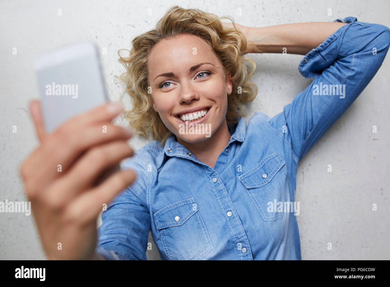 Ritratto di sorridere donna bionda tenendo selfie con lo smartphone Foto Stock