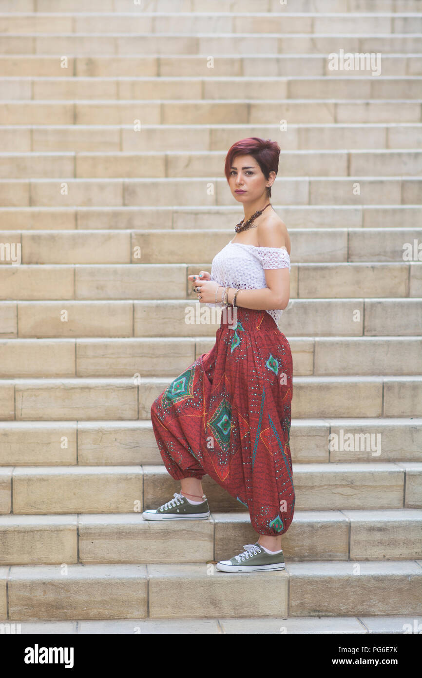 Giovane e bella donna che indossa pantaloni harem in piedi sui gradini  esterni Foto stock - Alamy