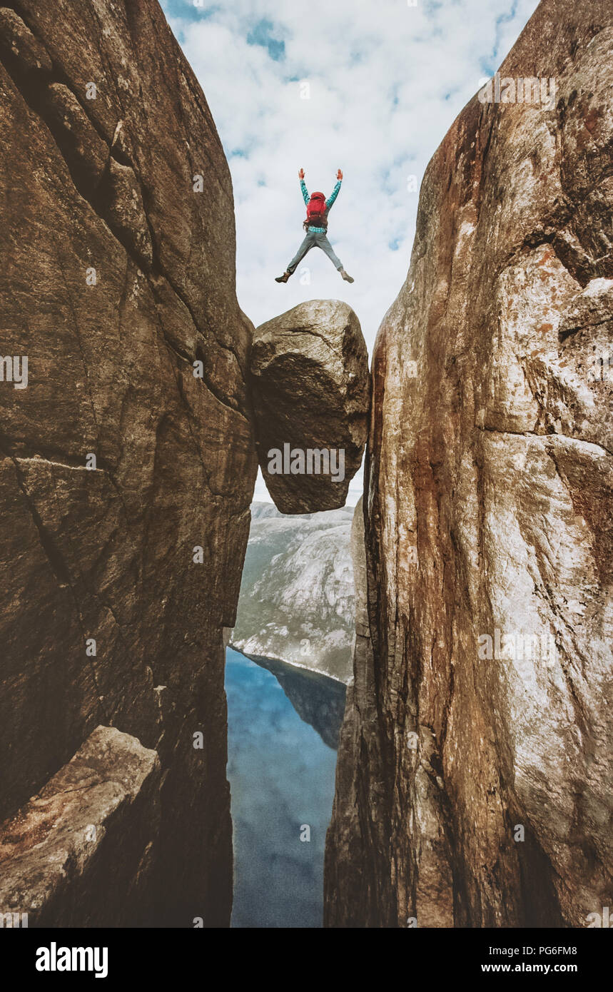 Uomo coraggioso saltando Kjeragbolten extreme viaggi in Norvegia Kjerag montagna vacanze estive avventura concetto di successo Foto Stock