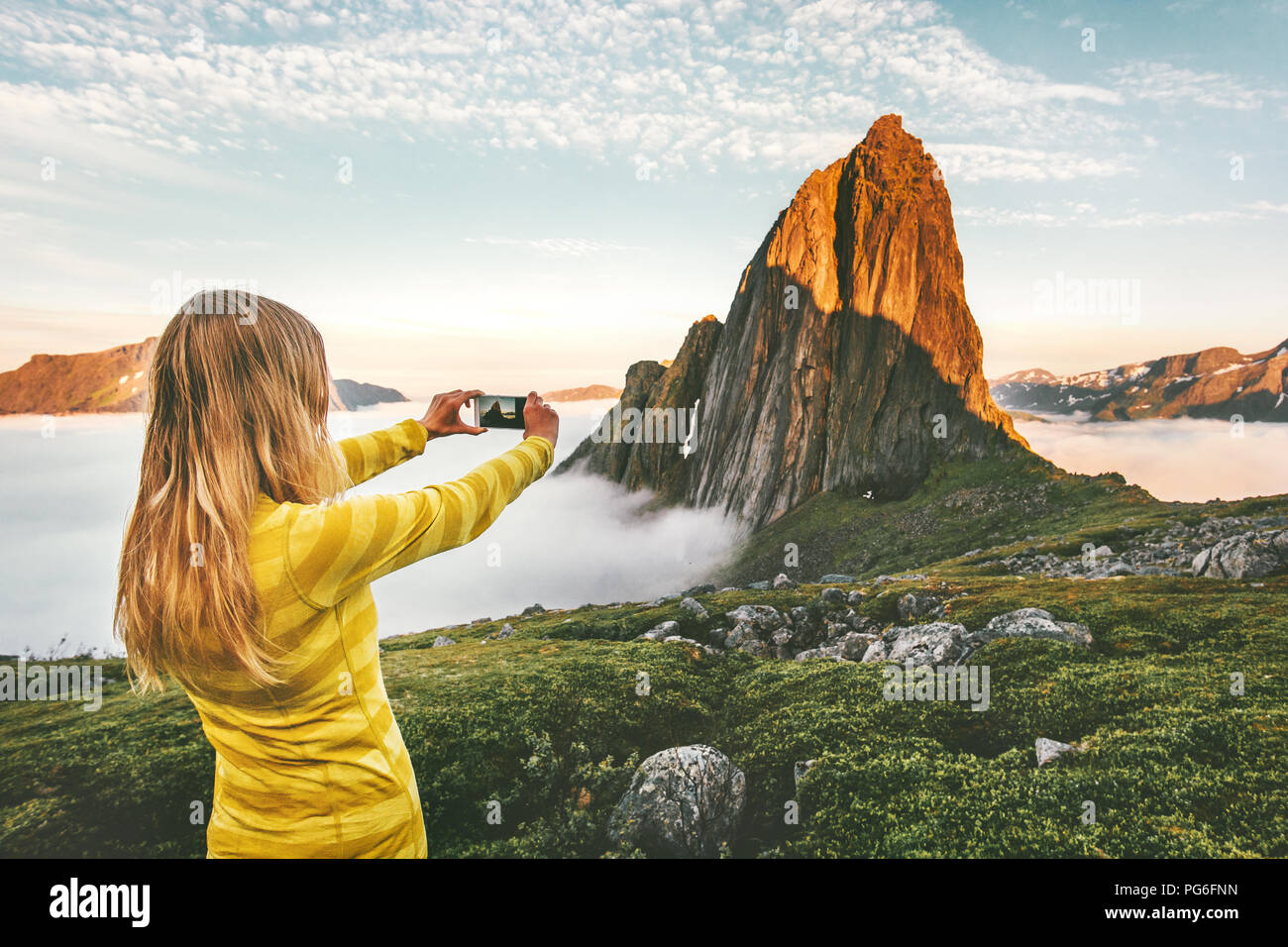 Donna traveler prendendo foto tramite smartphone esplorando il tramonto montagne rocciose in Norvegia viaggio d avventura vacanze estive in viaggio lifestyle Foto Stock