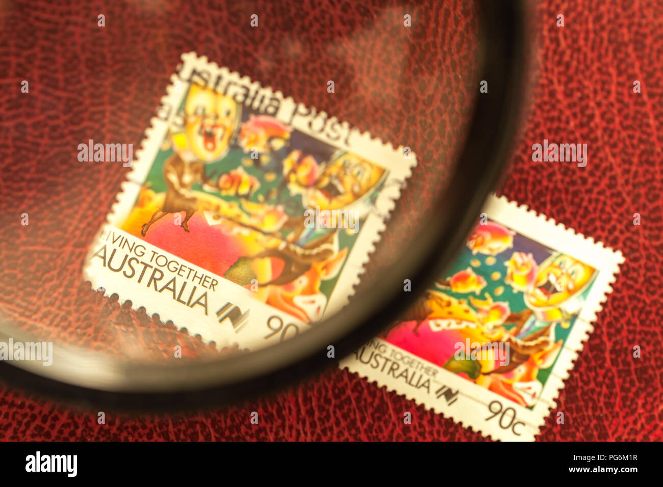 Australian francobolli sotto la lente di ingrandimento, con la texture di sfondo di borgogna. Foto Stock