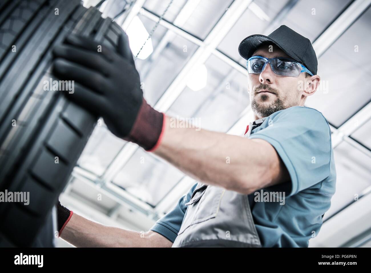 Nuovi pneumatici per auto l'acquisto. Negozio caucasica lavoratore cercando pneumatico destro. Stagionale di manutenzione del veicolo. Foto Stock