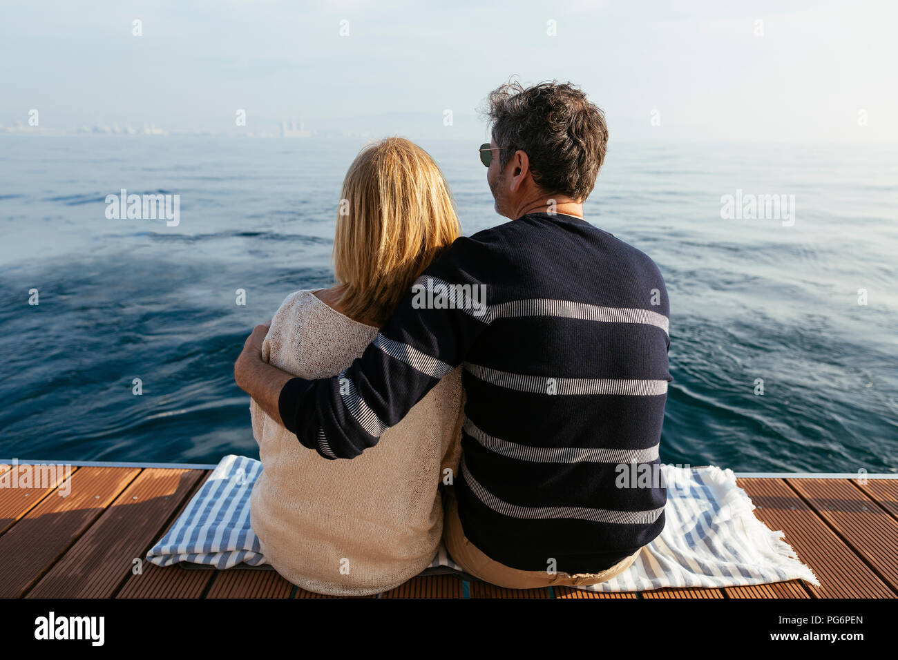 Coppia matura seduta sul molo, rilassante al mare Foto Stock