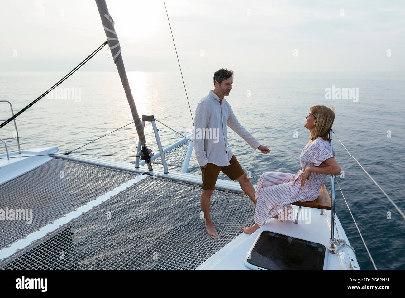 Coppia matura in piedi sul catamarano trampolino, godendo il loro viaggio in barca a vela Foto Stock