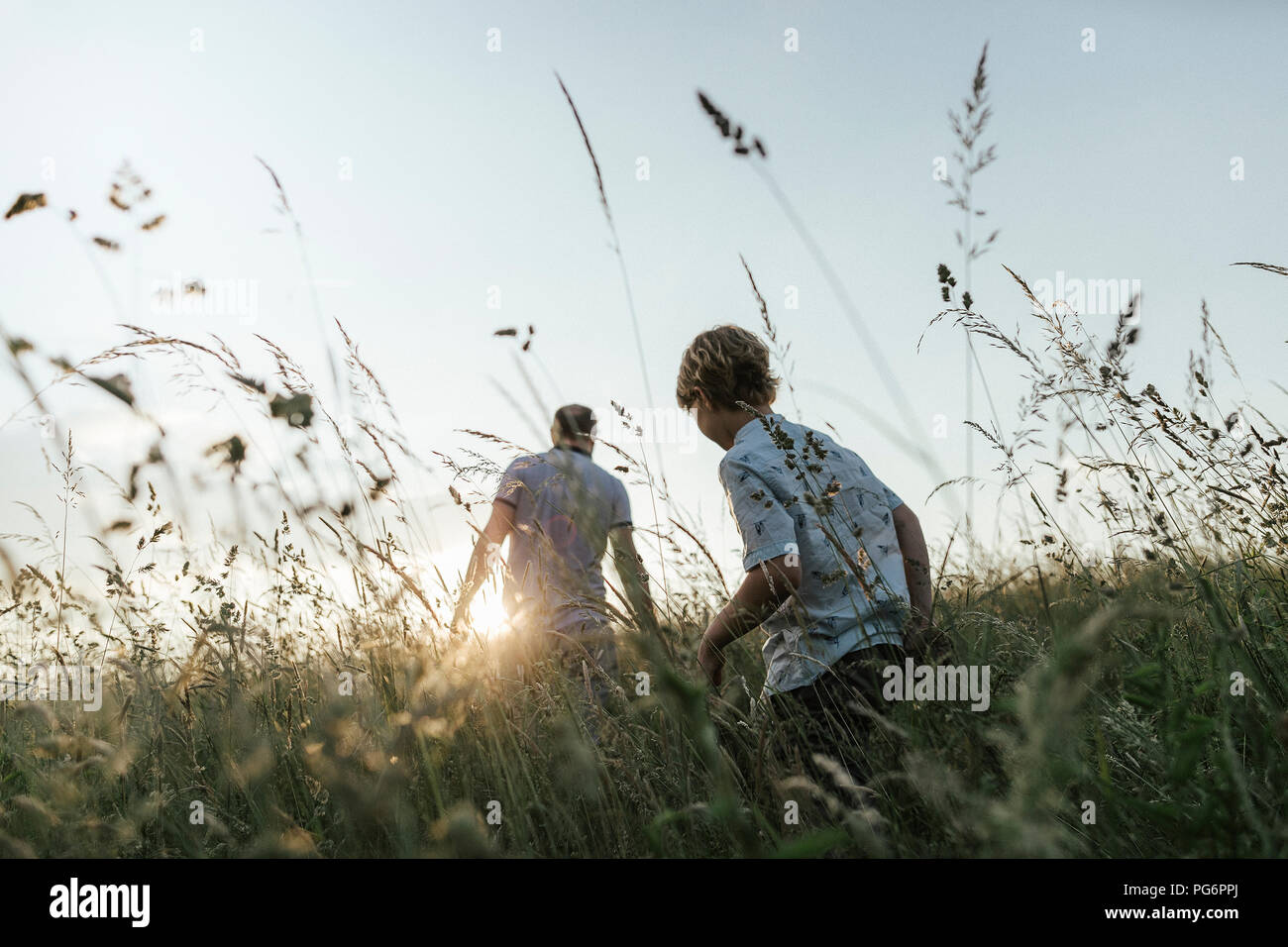 Ragazzo e suo padre a piedi nella natura al tramonto Foto Stock