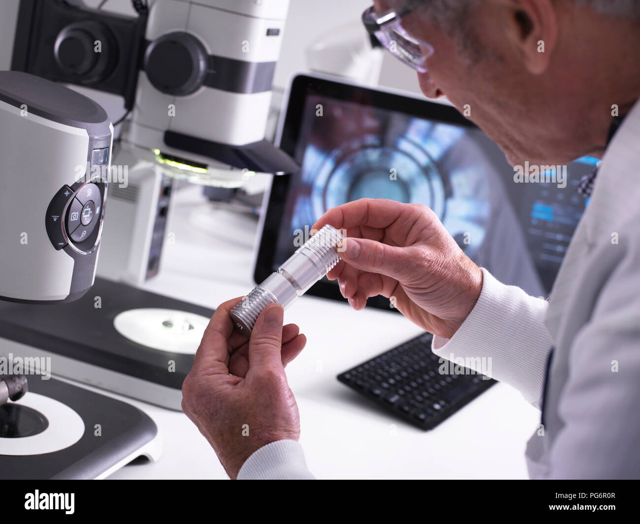 Ingegnere usando un 3D stereo microscopio per il controllo della qualità nella fabbricazione di componenti per l'industria Foto Stock