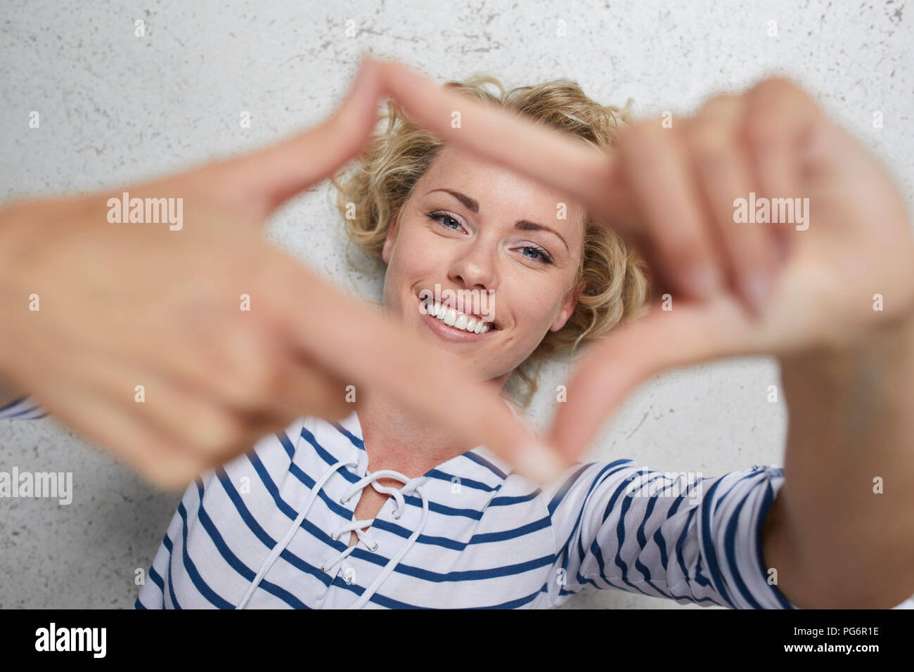 Ritratto di sorridere donna bionda telaio conformatore con le dita Foto Stock