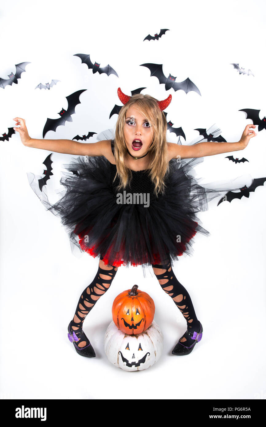 Bambina con un demone costume diavolo vestito di nero vestito rosso e rosso diavolo corna per pumpkin patch e la festa di Halloween, posa con felice smi Foto Stock