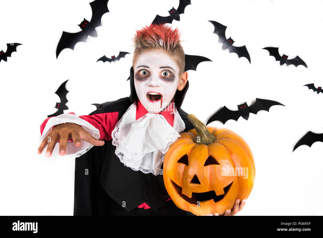 Scary Halloween vampire boy vestite per spooky Halloween party e la tenuta di un arancione zucca di halloween jack o lantern Foto Stock
