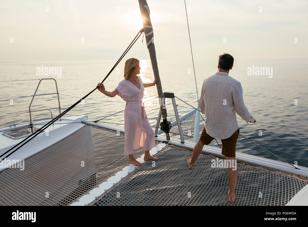 Coppia matura in piedi sul catamarano trampolino, godendo il loro viaggio in barca a vela Foto Stock