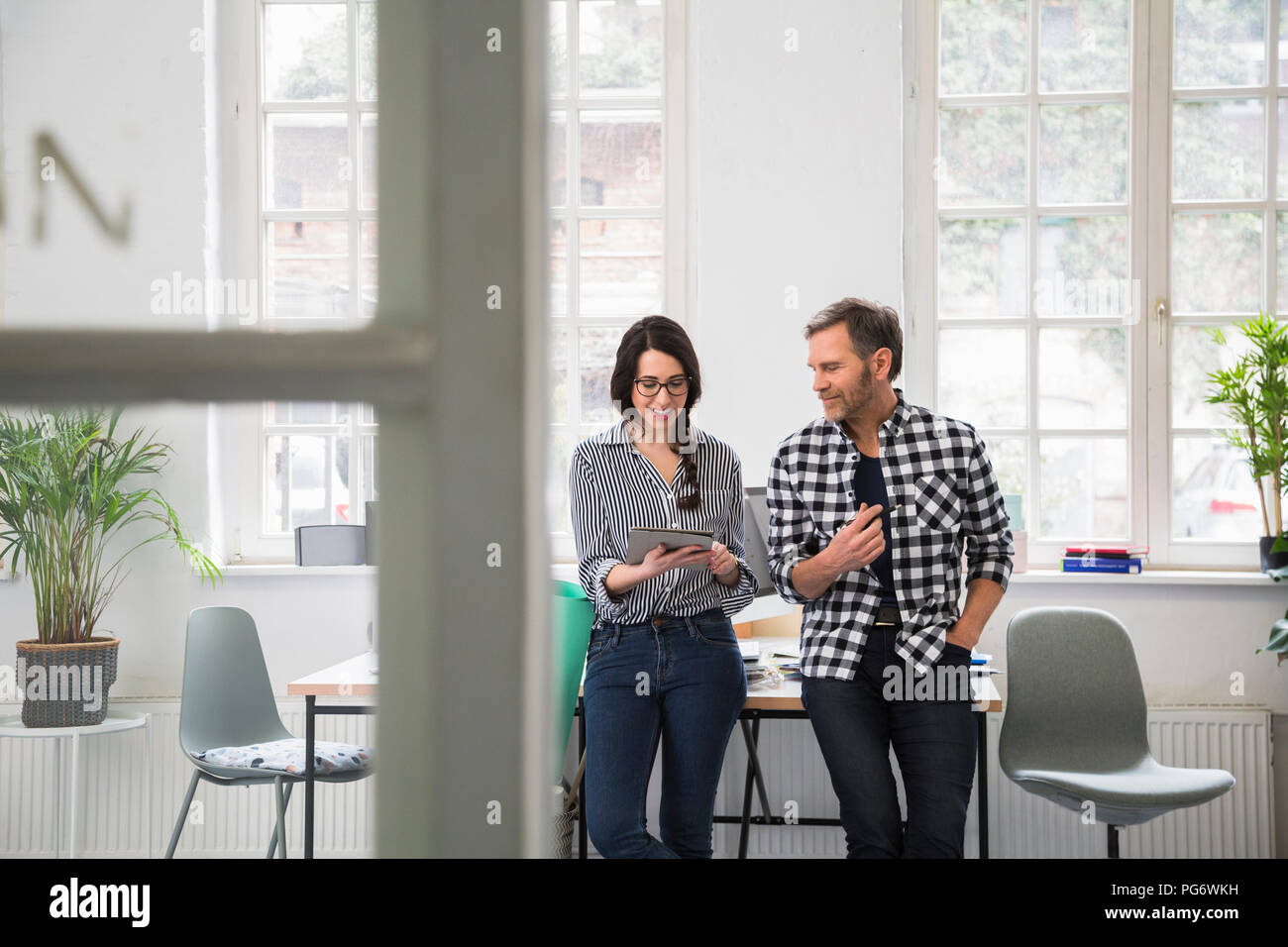 I colleghi utilizzando il tablet in un ufficio loft Foto Stock