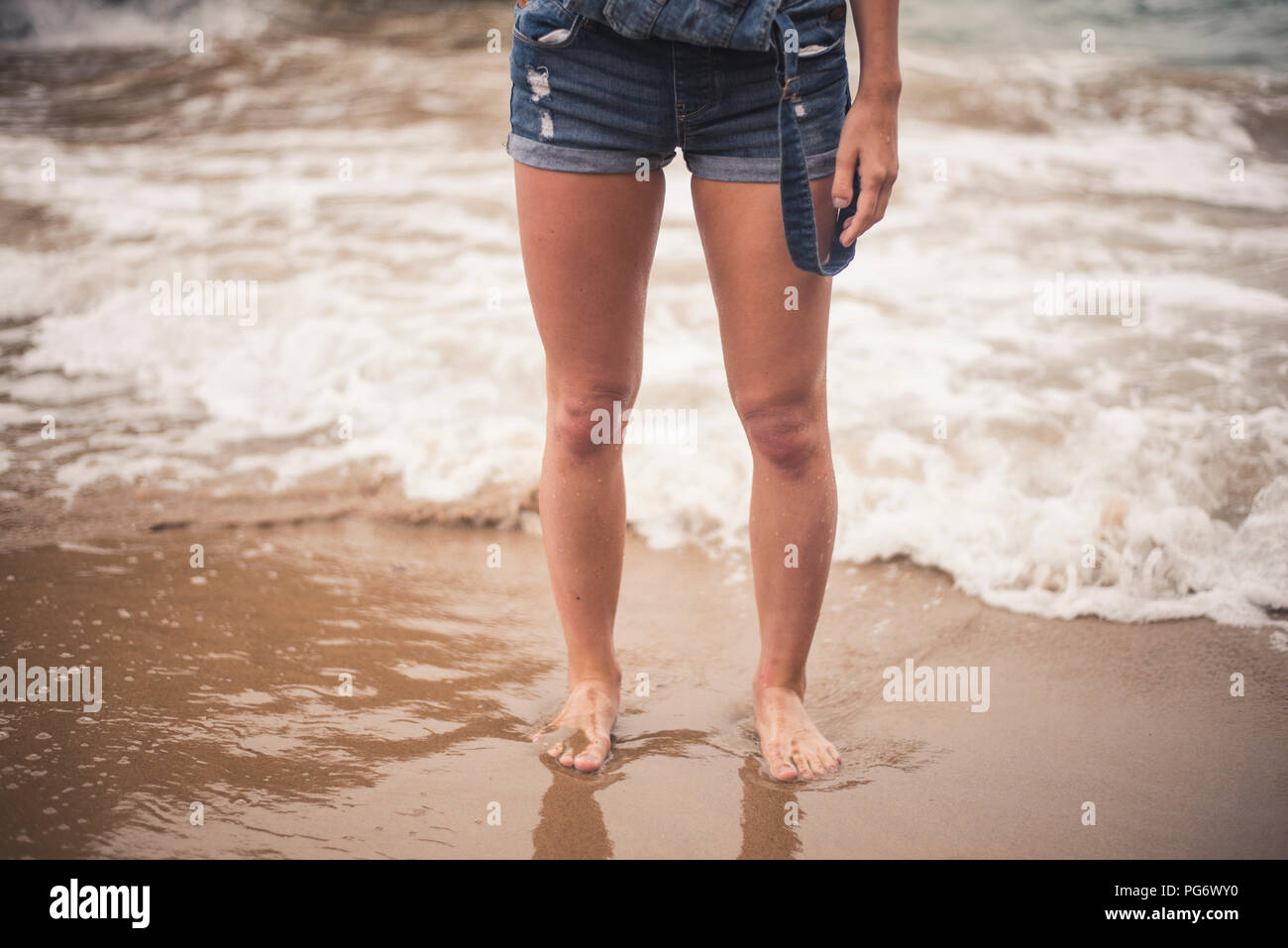 Le gambe della giovane donna in acqua su una spiaggia Foto Stock