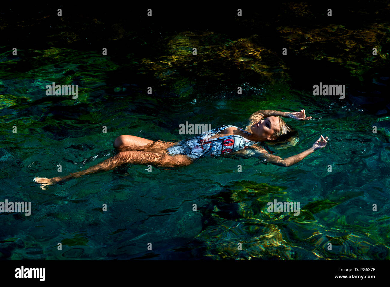 Giovane donna galleggiante sull'acqua in laguna Foto Stock