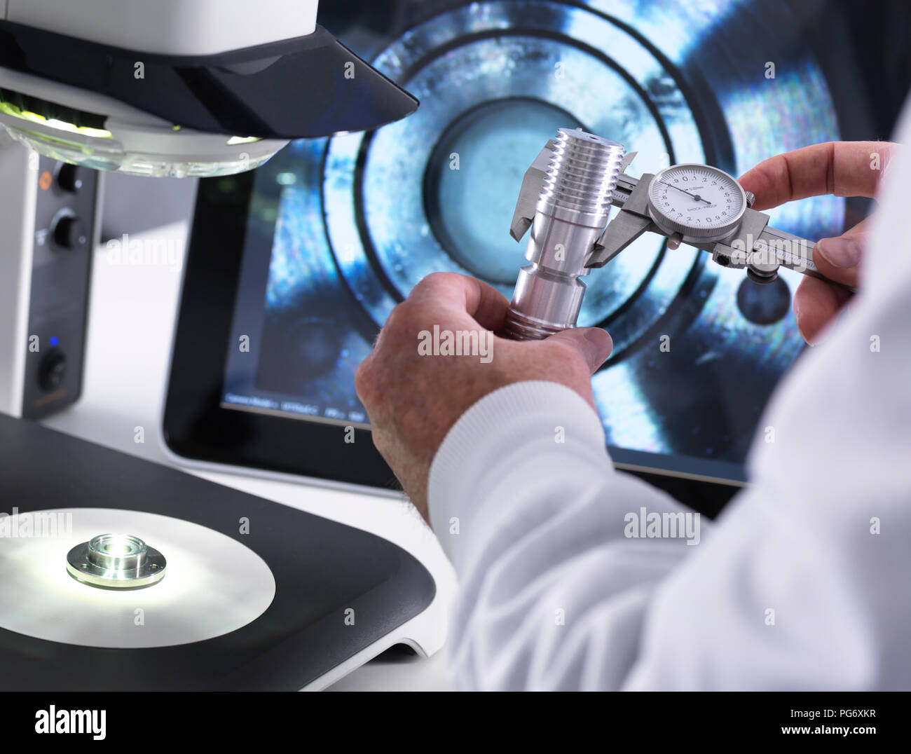 Ingegnere utilizzando una pinza e un 3D stereo microscopio per il controllo della qualità nella fabbricazione di componenti per l'industria Foto Stock